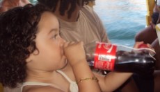 Little Brazilian girl drinking a full bottle of Coca-cola